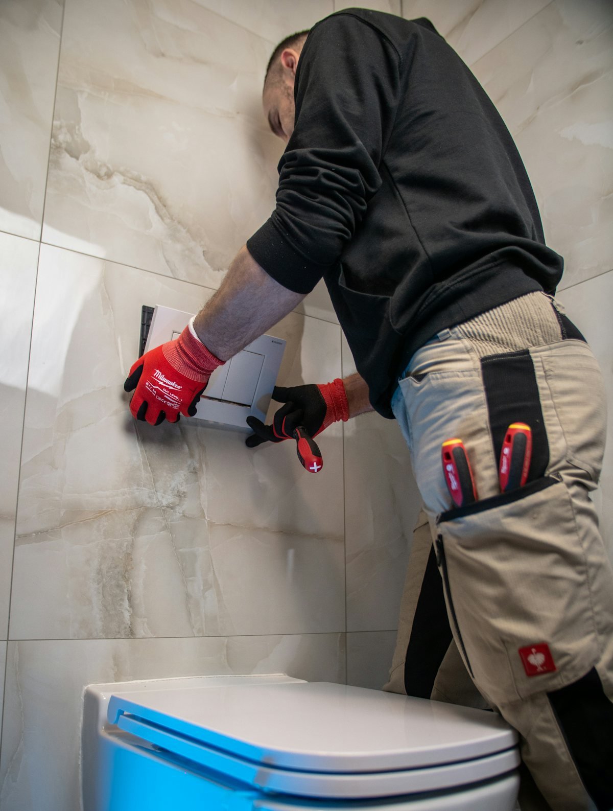 Plombier installant la plaque de commande d'un WC suspendu